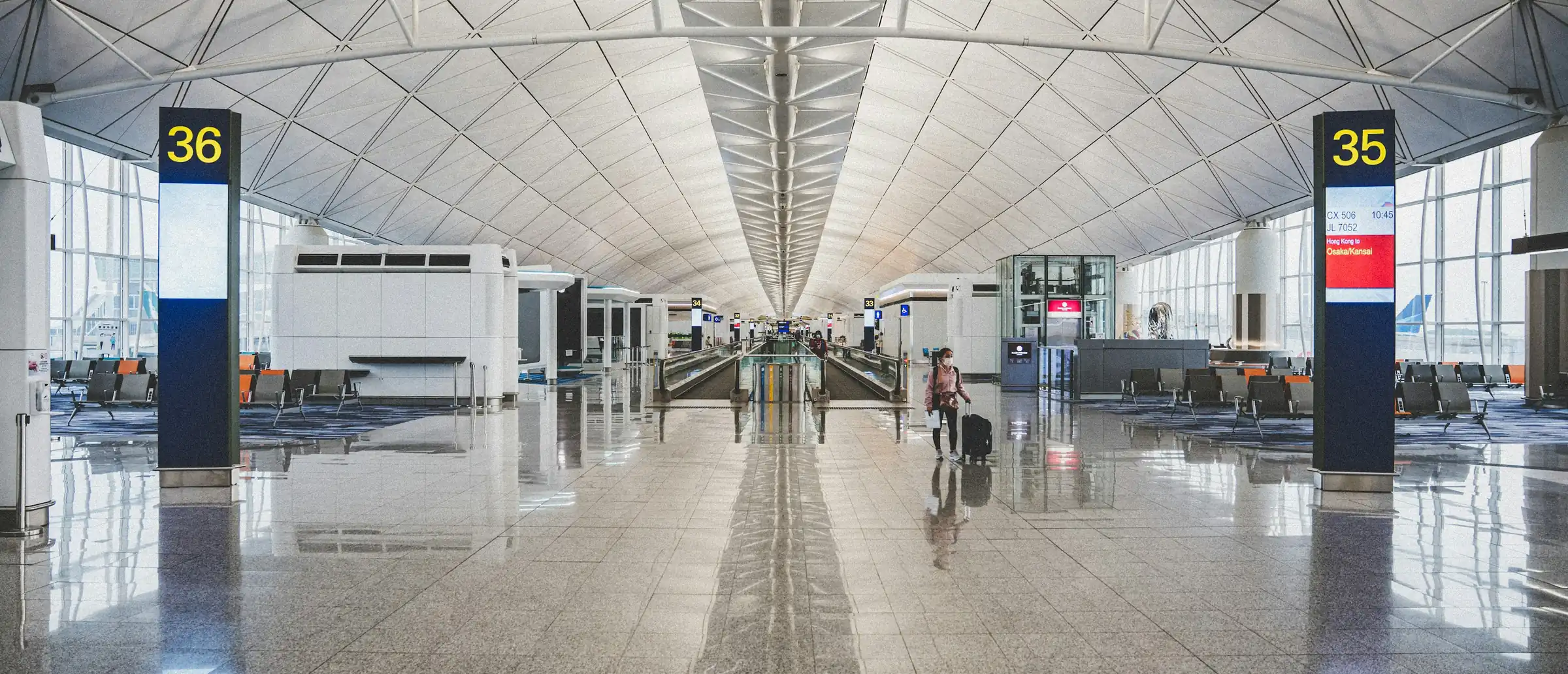 A gate sign reading 35 in a bright, near-empty airport terminal, flight numbers and times below it.